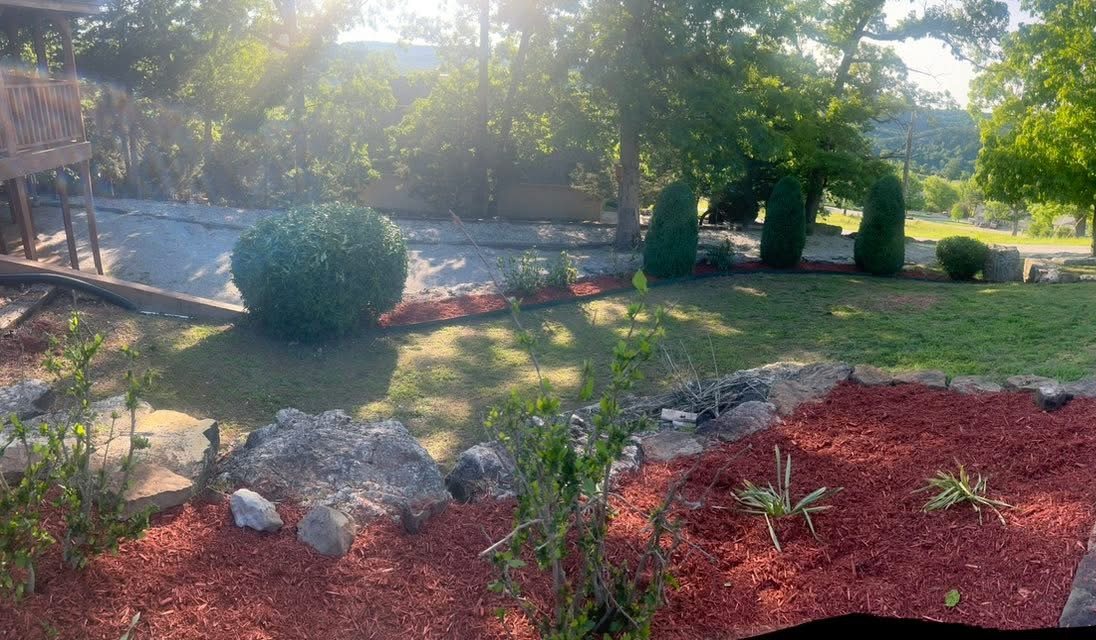 Fresh red mulch laid around a stone-edged hillside bed