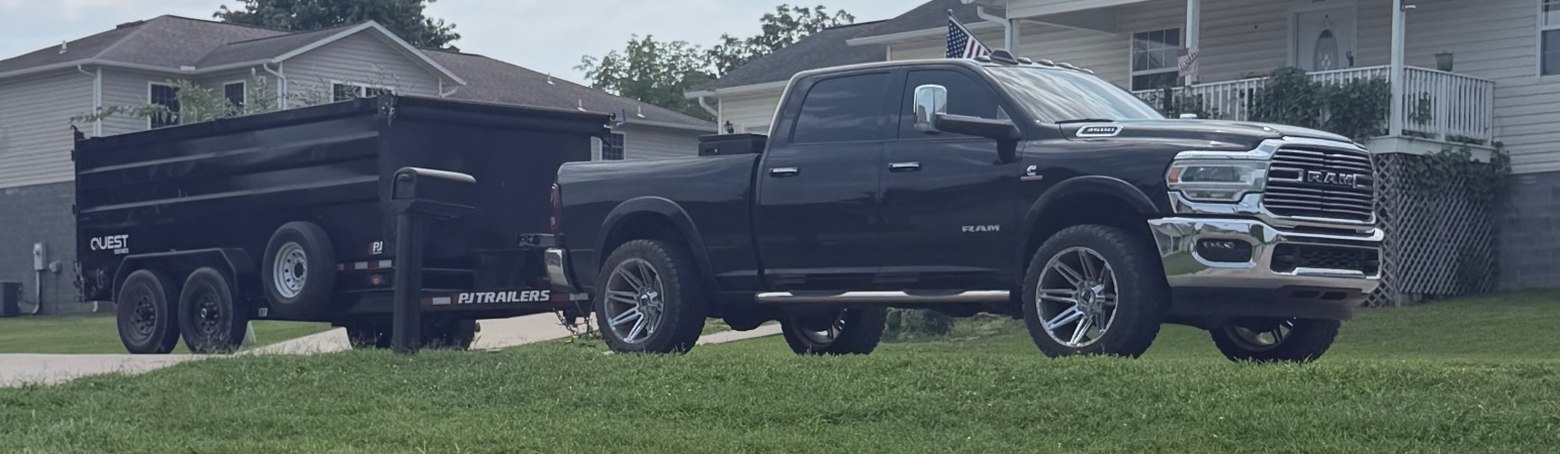 Black pickup and black dump trailer parked on a lawn, ready to load